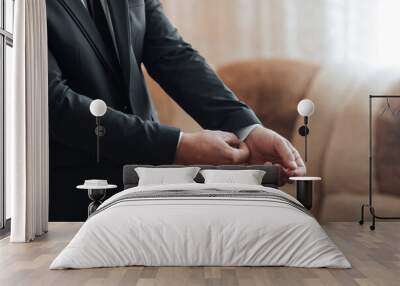 A man in a suit is getting ready for a formal event. He is adjusting his tie and shirt, and his hands are visible. Concept of preparation and formality Wall mural