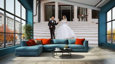 portrait of the newlyweds in classic wedding clothes on a large beautiful staircase. the concept of stores and sales of goods for the bride and groom. Wall mural