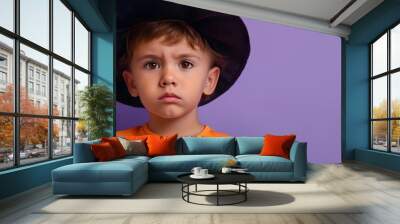 Boy in orange shirt and black hat on purple background. Halloween costume and children fashion marketing Wall mural