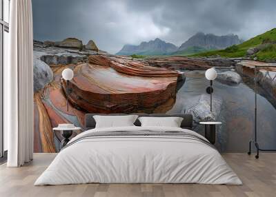 Eroded rock formations with colorful layers in mountain stream. Misty peaks in background under stormy sky Wall mural