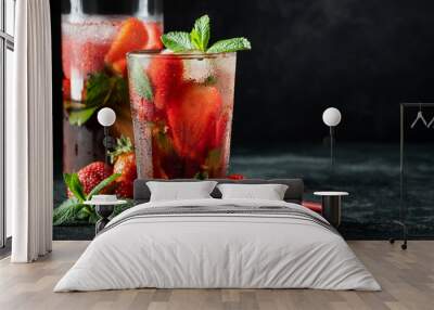 Fresh lemonade with ice, mint and strawberry on top in glass on black table background, copy space. Cold summer drink. Sparkling glasses with berry cocktail Wall mural