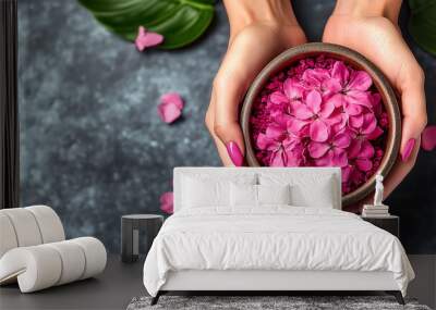 Hands holding bowl of vibrant pink flower petals. Luxurious aromatherapy and skincare treatment. Banner with copy space Wall mural