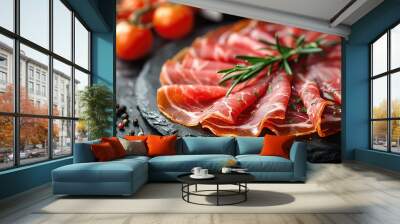 Slices of prosciutto di parma or jamon serrano (iberico) on a black plate on a dark slate Wall mural