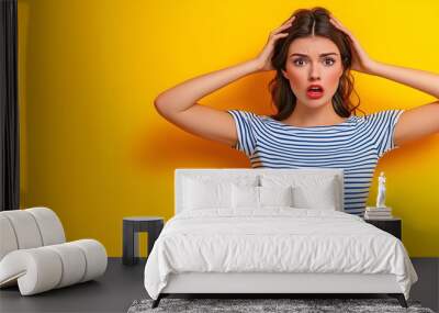 Surprised young woman in striped shirt with hands on head against vivid yellow background for shock and disbelief concept designs Wall mural