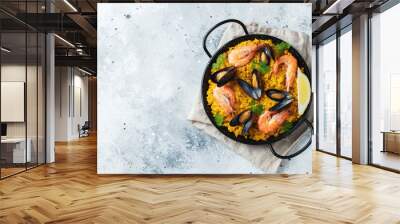 Traditional spanish seafood paella in pan with chickpeas, shrimps, mussels, squid on light grey concrete background. Top view with copy space Wall mural