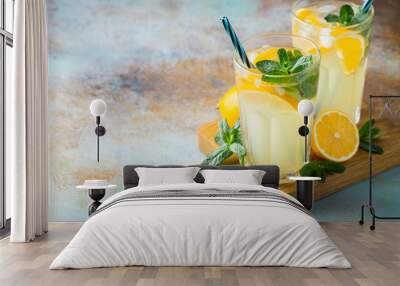 Two glass with lemonade or mojito cocktail with lemon and mint, cold refreshing drink or beverage with ice on rustic blue background. Copy space Wall mural