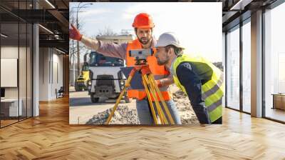 two male surveyor engineer with a device working on a construction site in a helmet Wall mural