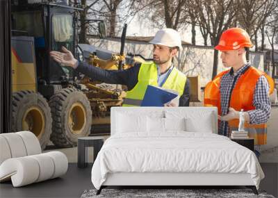 two men are builders workers are engineers at a construction site are looking at the drawings in helmets Wall mural