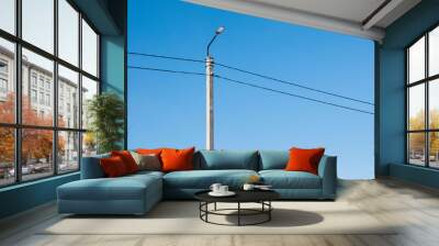 Electric pole and high voltage wires against the blue sky. Industrial landscape Wall mural