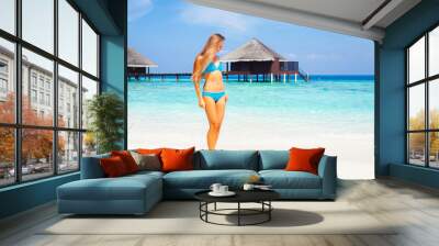 Young attractive blonde girl with perfect sport body in bikini on the tropical summer beach at resort Wall mural