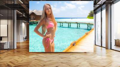 Young attractive blonde girl with perfect sport body in bikini on the tropical summer beach Wall mural