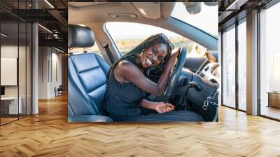 Happy smiling african girl in black striped clothes is driving a car Wall mural