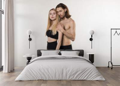 Heterosexual couple, handsome man with long hair and naked torso and his beautiful girlfriend in black skirt hugging Wall mural