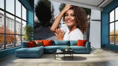 Portrait of smiling european woman with brunette curly hair Wall mural