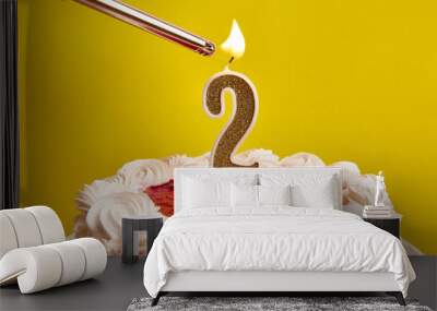 A candle in the form of the number 2, stuck in a festive cake, is lit. Celebrating a birthday or a landmark event. The climax of the celebration. Wall mural