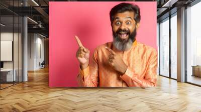 A joyful man in traditional attire pointing and smiling against a pink background during a festive celebration. Generative AI Wall mural