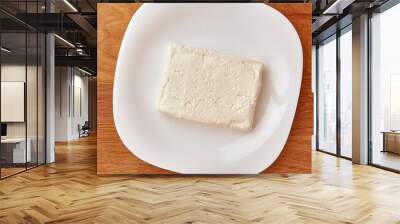 A slice of sour milk cheese on a white plate. Wall mural