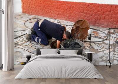 Worker cleans the drains hatch and removes dirt and debris from the sewer. Plumber cleans the sewer Wall mural