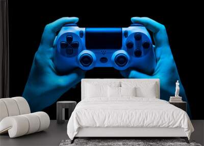 Hyman hands holding white video game gamepad in neon lights isolated on a black Wall mural