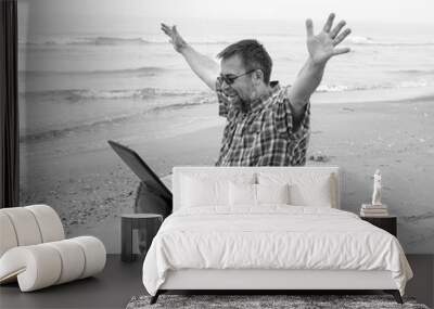 Emotional  businessman with laptop on the beach Wall mural