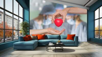 Heart transplant and organ donation concept. Hand is giving red heart. Wall mural