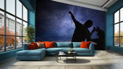 Silhouettes of people observing stars in night sky. Astronomy concept. Wall mural