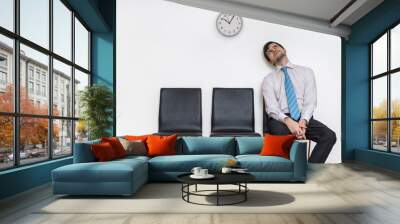 Tired and exhausted man is sitting in waiting room on chair. Wall mural