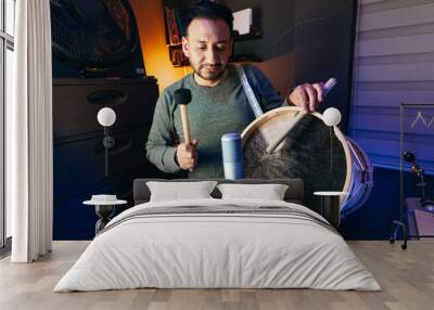 man concentrating on playing the Andean bass drum in a home recording studio Wall mural