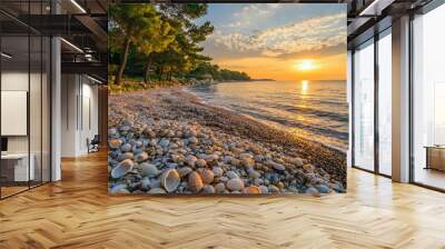 the coast is the sea with an embankment, a beach made of stones and shells, sunrise, trees on the left Wall mural