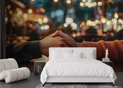 Two hands clasped together gently, with a soft focus on the background of a cozy cafÃ© setting. Wall mural