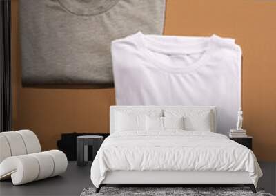 Close up of folded t shirts and white sneakers and copy space on brown background Wall mural