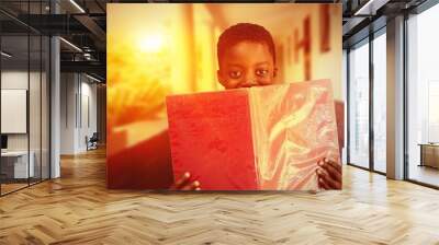 Composite image of cute boy reading book in library Wall mural