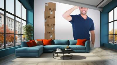 Composite image of portrait of happy delivery man wearing cap Wall mural