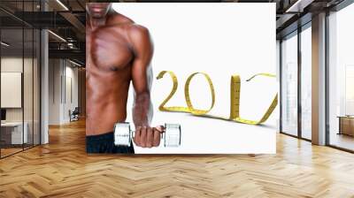 Composite image of serious fit shirtless young man lifting dumbb Wall mural