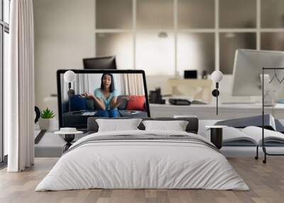 Mixed race female woman having video call on screen of laptop on desk Wall mural