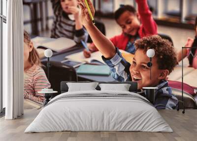 Schoolkids raising their hands in classroom Wall mural