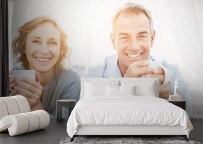 Smiling middle aged couple sitting on the couch having coffee Wall mural