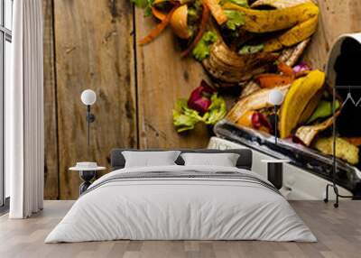 Vertical image of organic fruit and vegetable food waste spilling from open kitchen composting bin Wall mural