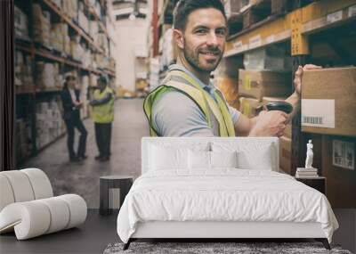 Warehouse worker scanning box while smiling at camera Wall mural