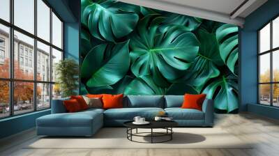 Flat lay of fresh monstera leaves creating a vibrant green pattern with their unique shapes and textures Wall mural