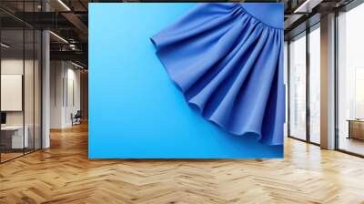 A close-up of a flowing blue skirt against a soft blue background, showcasing the texture and elegance of the fabric. Wall mural