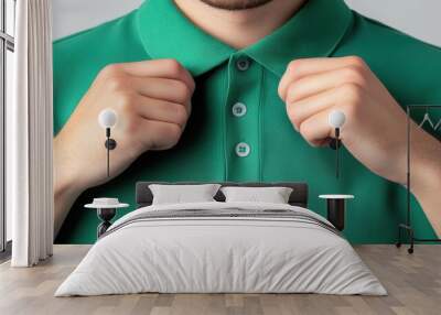 Close-up of a person adjusting a green polo shirt, emphasizing style and comfort in casual wear. Wall mural