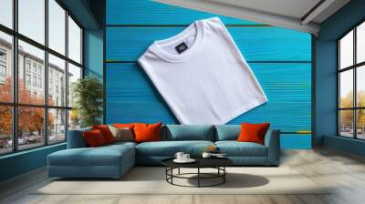 Minimalist flat lay of a folded white t-shirt on a vibrant blue wooden surface, perfect for fashion or product promotion. Wall mural