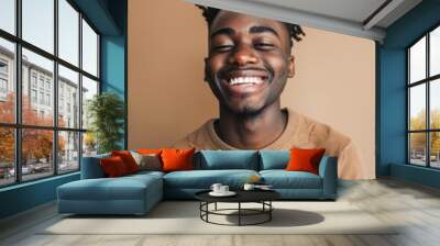 A cheerful young man with a beard, smiling broadly. He is dressed in casual attire and appears relaxed in an urban setting. Wall mural