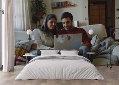 A man and a woman sit together on the couch using their laptop, smiling and looking at the screen. Wall mural