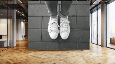 A person standing on a brick sidewalk in casual attire, featuring white sneakers Wall mural