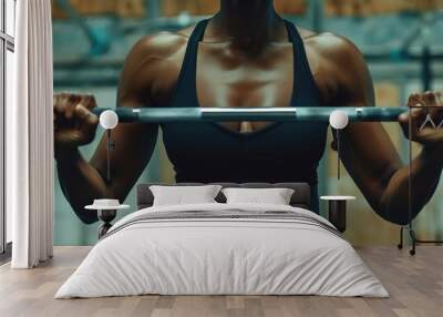 A woman in a black athletic top working out with weights at the gym. Wall mural