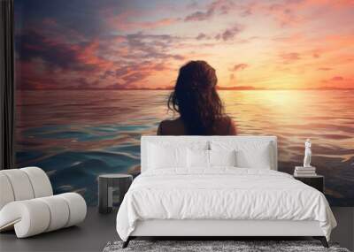 A woman is in the ocean at sunset. The water is calm and the sky is filled with beautiful colors. The woman is looking out at the horizon, taking in the beauty of the moment Wall mural