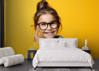 A young girl wearing glasses and a yellow sweater. Perfect for educational or back-to-school concepts. Wall mural