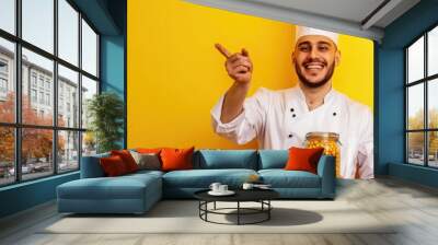 Chef in uniform smiling at camera, suggesting a happy working atmosphere. Wall mural